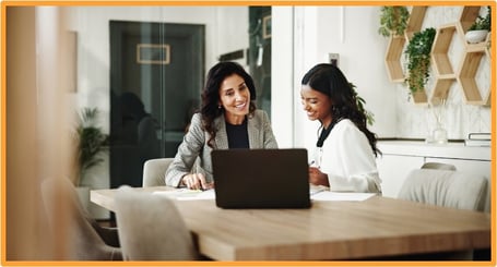 Two business professionals discussing tax planning strategies at an office desk with a laptop and financial documents, illustrating collaborative tax advice for business owners.