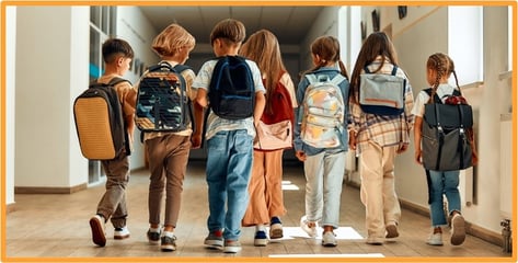 A group of elementary school children wearing backpacks walks down a school hallway, highlighting the expanded 529 plan benefits for K-12 education expenses under the OBBBA.