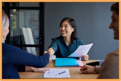 Smiling woman shaking hands with a candidate during a job interview, representing the hiring process eligible for the Work Opportunity Tax Credit.