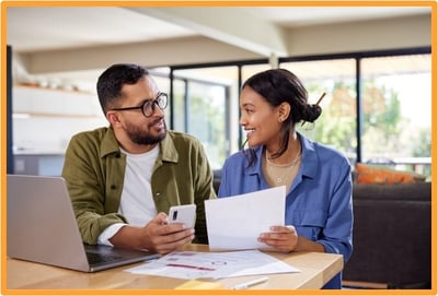 Young couple reviewing financial documents together at home, portraying investors planning their finances and discussing the potential tax advantages of QSB stock.