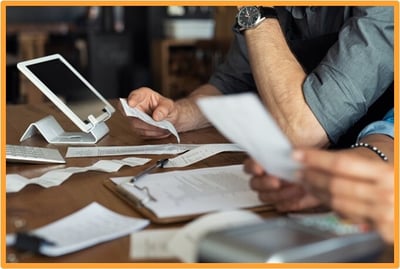 Close-up of businesspeople reviewing receipts and expense reports at a desk, illustrating the process of documenting business expenses for reimbursement