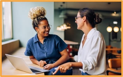 Two business professionals discussing tax strategies and recent R&E expensing changes while working together on a laptop in a modern office
