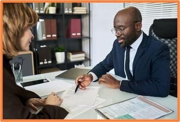 Financial advisor discussing tax documents with a client in an office, symbolizing professional guidance for understanding and managing AMT exposure.