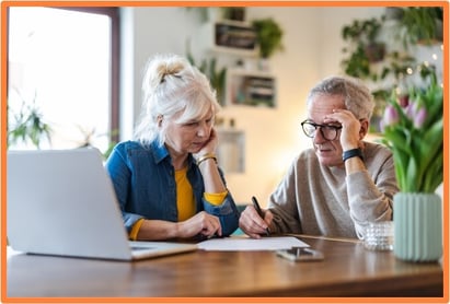 Older couple reviewing financial documents together at home, illustrating the importance of planning when to start receiving Social Security benefits