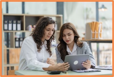 Two professional women discussing tax strategies on a laptop, illustrating collaboration with a tax advisor to maximize benefits from recent changes to Opportunity Zone incentives.