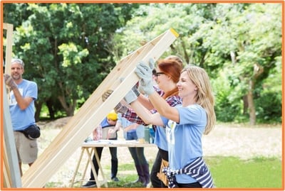 Volunteers working together to build a structure for a nonprofit project, illustrating out-of-pocket supply and uniform expenses that can qualify for tax deductions.