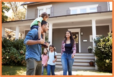 Happy family standing together in front of their home, illustrating the importance of protecting loved ones and assets through estate planning.
