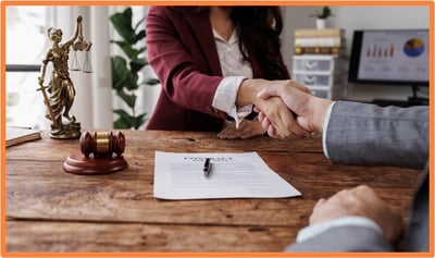 Estate planning advisor and client shaking hands over a signed contract, representing a successful estate planning meeting.