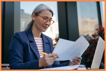 Business professional reviewing financial documents and equipment purchase options, considering whether to buy or lease assets for their company.