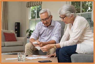 Senior couple reviewing bills and paperwork at home, illustrating year-end tax planning and strategies for individuals age 65 and older.