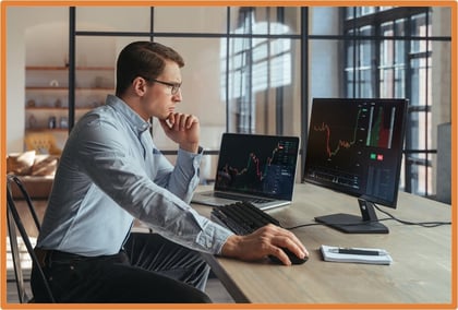 Investor analyzing stock charts on computer screens, highlighting tax planning strategies for managing investment gains and losses before year-end.