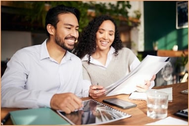 Two business professionals reviewing financial documents together at a desk, symbolizing collaboration in understanding new IRS 1099 reporting requirements for independent contractors and businesses.