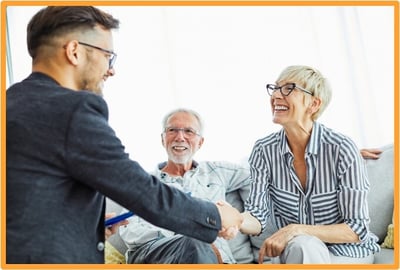A smiling senior couple meeting with a financial advisor, symbolizing tax planning and new deductions for retirees.