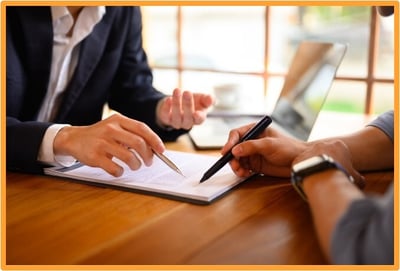 Two professionals reviewing and discussing tax documents at a desk, illustrating a tax advisor helping a client with tax planning.