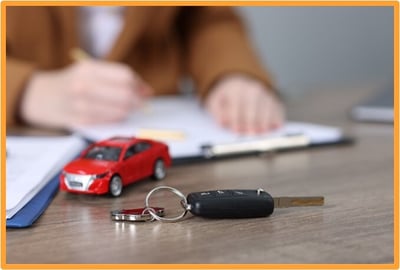 Car keys and a model car on a desk with paperwork in the background, symbolizing the new tax deduction for car loan interest.