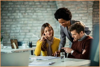 Diverse group of professionals reviewing financial documents together in a modern office, symbolizing collaborative financial planning and consulting with advisors about Roth 401(k) contributions.