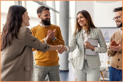 Group of business professionals celebrating and shaking hands in a modern office, representing successful partnerships and decision-making in forming start-up entities.