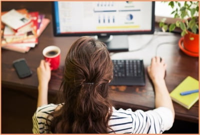 Small business owner working at a desk with financial charts on a computer screen, illustrating the need for research, financial planning, and effective operations management for a new business.