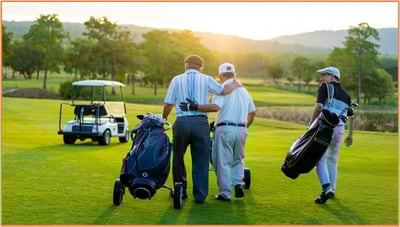 Business associates walking together with golf bags on a golf course, representing entertainment expenses like golf outings that are generally not deductible under current tax law.