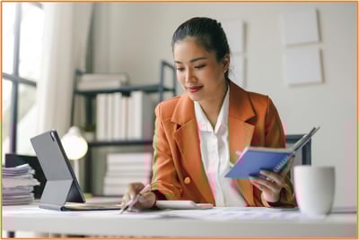 Professional woman working at her desk with a digital tablet and notebook, illustrating the importance of tax planning and staying updated on evolving tax regulations for individuals.