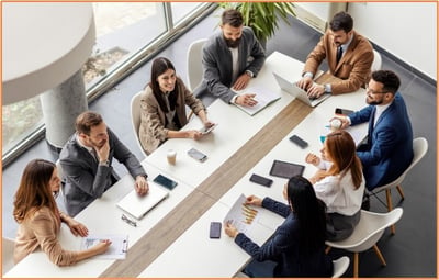Corporate leadership team discussing business restructuring strategies around a conference table, representing the decision-making process involved in F reorganizations for tax efficiency.