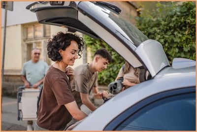 Family packing the trunk of a car with luggage, preparing for a road trip, representing the planning and preparation needed for a successful journey.