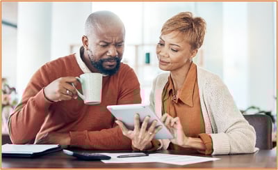 "Middle-aged couple reviewing tax documents and information on a tablet, representing individuals preparing for new tax changes and deductions in the 2025 tax season."
