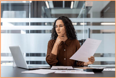 Woman carefully reviewing financial documents at her desk, illustrating the importance of understanding tax compliance and passive activity loss rules for limited partnership investments.
