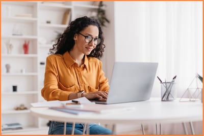 A self-employed woman working from home on her laptop, illustrating an entrepreneur or sole proprietor reviewing retirement plan choices and contributions for her small business.