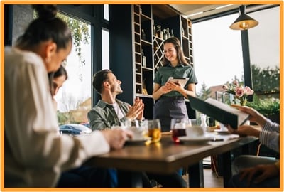 Waitress taking an order from smiling customers in a restaurant, illustrating tip income eligible for a new tax deduction