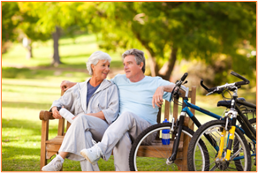 Active senior couple enjoying retirement outdoors, sitting on a park bench with their bicycles, representing the benefits of smart retirement planning.
