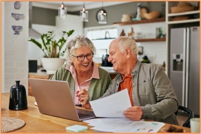 Senior couple reviewing financial documents together at home, planning retirement account options and rollover strategies on their laptop.