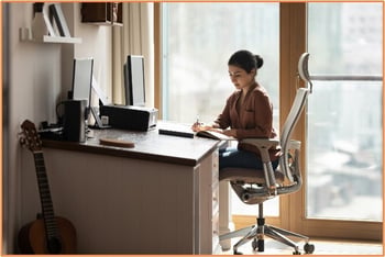 A woman works at a dedicated home office desk, illustrating a qualified space for the home office tax deduction.