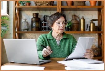 Mature woman reviewing conservation easement documents at her desk, illustrating the careful legal and financial considerations involved in land protection.
