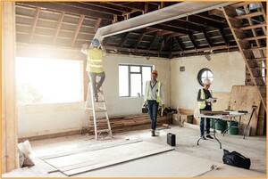 Workers in safety vests repairing the interior of a damaged home, illustrating post-disaster reconstruction and the types of property losses that may qualify for casualty loss tax deductions.