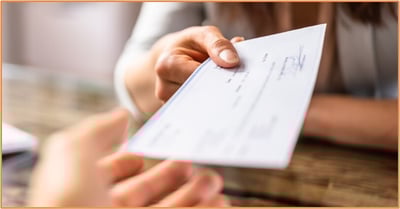 Person handing a check to another individual as a charitable donation.
