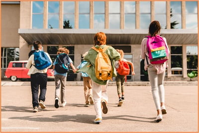 Group of school children with backpacks entering a school building, symbolizing saving for children’s future needs and education with 530A accounts.