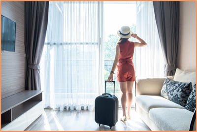 Woman with a suitcase preparing to leave her home, symbolizing renting out a house for extra income during a summer event for potential tax savings.