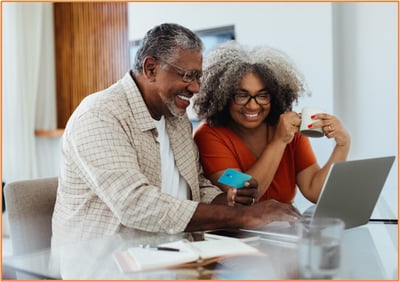 Happy retired couple reviewing their estate documents and making tax planning decisions together at home.
