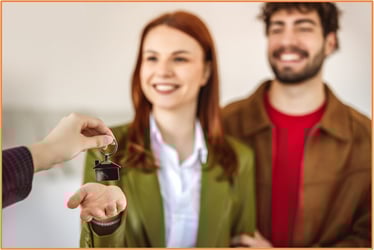 Smiling young couple receiving house keys, representing the opportunity for heirs to use inherited assets, such as stock or property, for important life milestones like purchasing a first home
