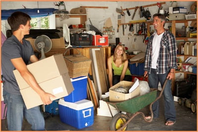 Family cleaning out a cluttered garage, preparing household items for donation as part of a summer cleanup for potential tax deductions.