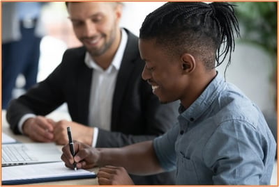 Student-athlete smiling while signing a contract or agreement with the guidance of a professional advisor, illustrating the importance of understanding the tax implications of NIL income and seeking expert advice.