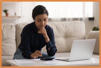 Small business owner working from home, calculating adjusted taxable income and reviewing tax documents related to business interest expense limitations using a laptop and calculator.